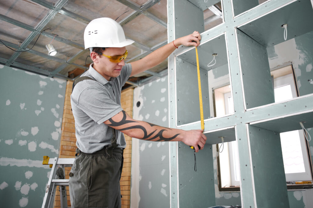 room repair. builder measures the cabinet with shelves using a tape measure on the background of the construction site