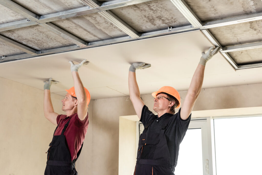 workers are attaching plasterboardto the ceiling.